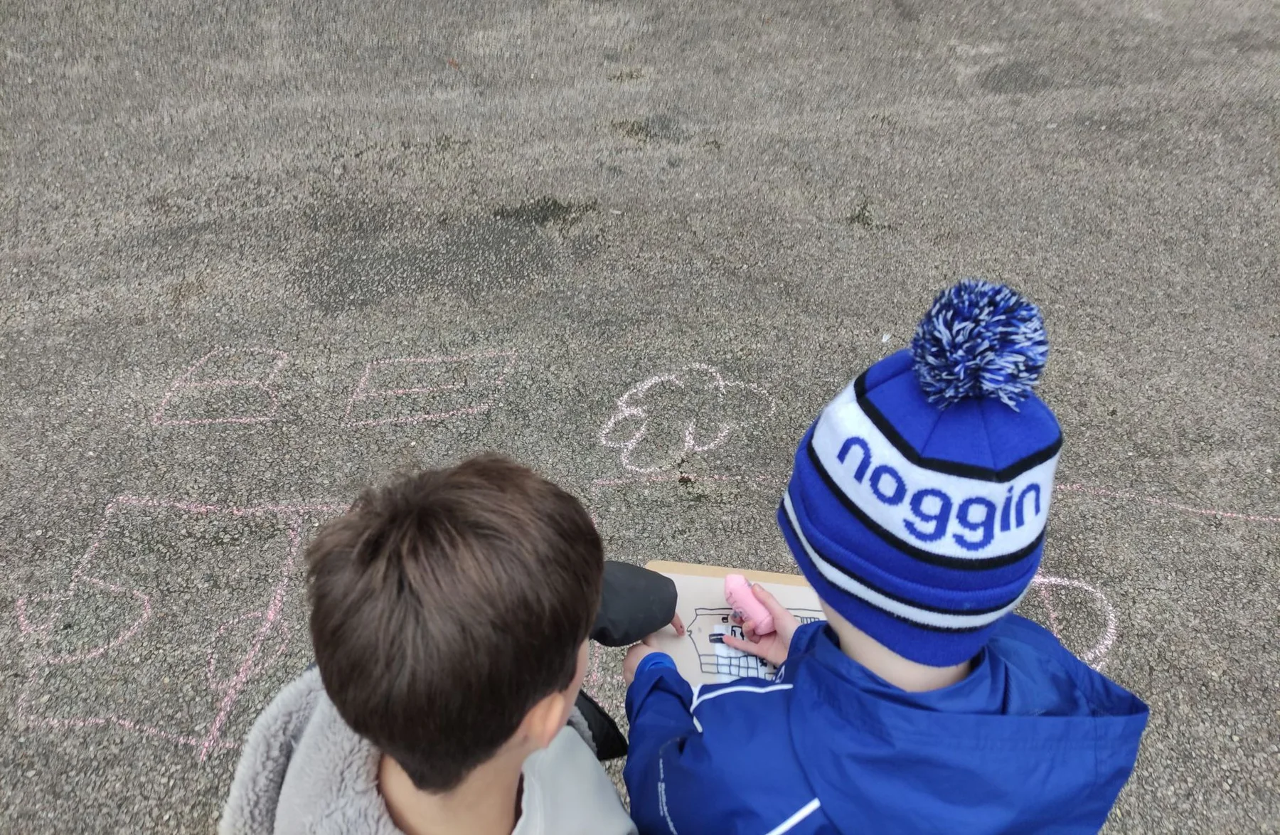 Children drawing and exploring ideas outdoors through a playful creative activity